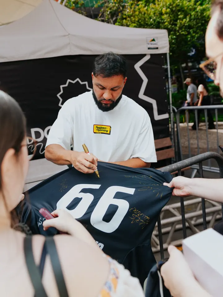 Jogador autografando uma camisa para fã no evento